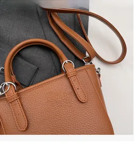 Detail of lychee pattern brown leather handbag showing silver buckles and fine stitching