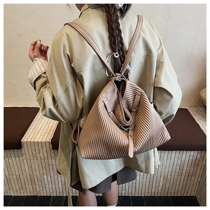 Detailed view of khaki pleated backpack with adjustable straps on female model
