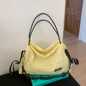 Detail of light yellow nylon tote bag with braided rope handle and fashion label