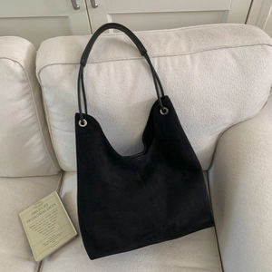 Detail of a large black suede hobo bag with silver eyelets and a long shoulder strap