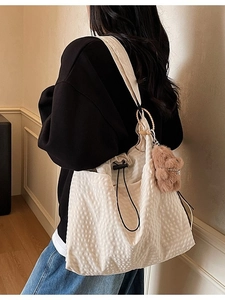 Minimalist creamy white drawstring bucket bag with quilted bubble texture and bear charm