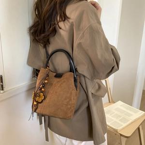 Detail of vintage brown suede bucket bag with wooden bead tassel on a khaki coat