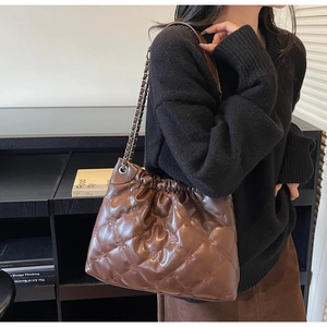 Détail d'un sac seau matelassé marron foncé avec bandoulière chaîne porté