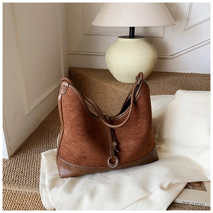 Detail of dark brown tote bag with matte suede texture and silver metal ring accents