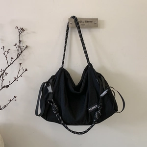 Detail of black canvas tote with woven rope strap and fashion patch on side