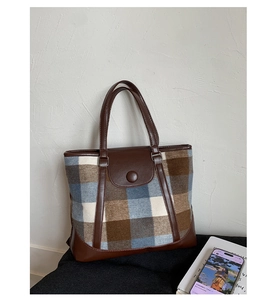 Detail of vintage plaid wool tote bag featuring brown leather trim and round buckle