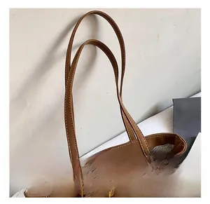 Detail showing the brown faux leather bag with contrast white stitching and metal rings