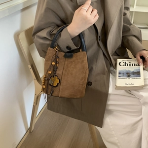 Detail of vintage matte brown bucket bag with wooden beads and floral charm accessory