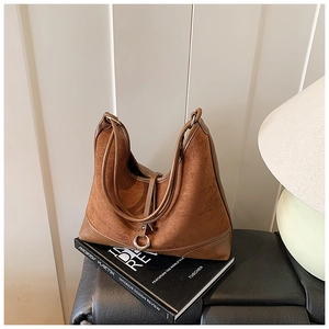Detail of a brown suede hobo bag with leather ribbons and metal ring decoration
