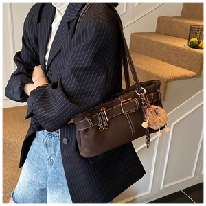 Detail of retro dark brown suede shoulder bag with plush pendant and metal buckle closure