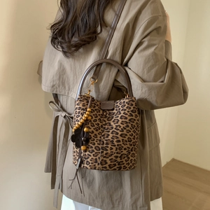 Detail of leopard print bucket bag featuring leather handles and chic floral bead charm