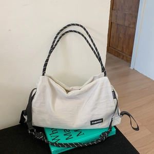 Detail of white nylon tote bag with rope handles on a book in an indoor setting