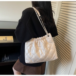Détail du sac seau matelassé beige avec bandoulière chaîne et finition texturée