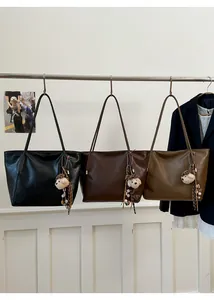 Trois grands sacs cabas en cuir noir, marron foncé et fauve avec des pendentifs chiots