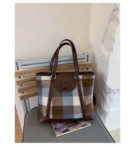 Detailed view of the plaid pattern fabric and brown leather strap on this large tote bag