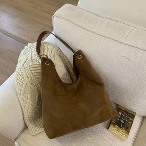 Detailed close-up of brown suede hobo bag with metal eyelets and large capacity design