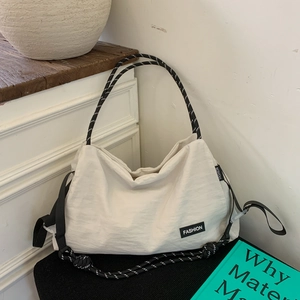 Detail of white large capacity tote bag featuring black fashion label and rope strap