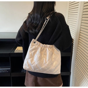 Détail du sac matelassé blanc cassé avec gaufrage floral et bandoulière chaîne argentée