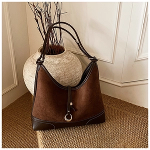 Detail of dark brown suede hobo bag featuring contrast stitching and silver metal buckle