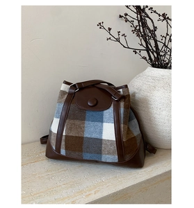 Detail view of vintage plaid wool fabric and dark brown leather trim on a tote bag