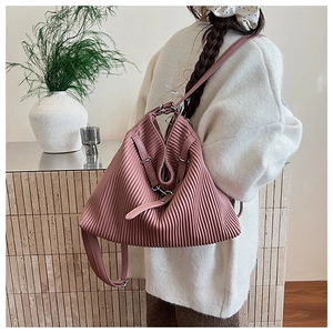 Detail of dusty pink pleated backpack on model wearing white knit sweater
