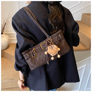 Detail of dark brown vintage shoulder bag with matte texture and cute teddy bear charm