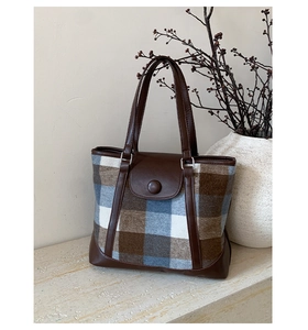 Detail of vintage plaid wool tote bag showing brown leather handles and corner protection