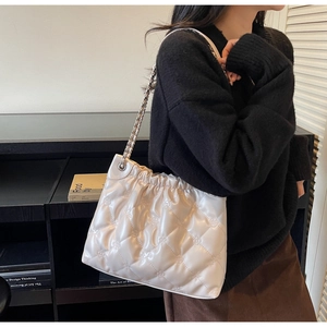 Détail du sac seau blanc matelassé avec motifs floraux en relief et bandoulière en chaîne