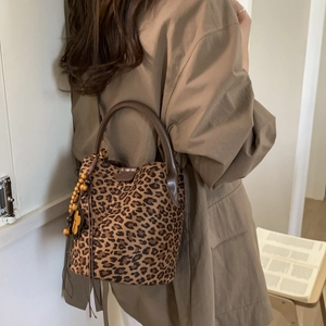 Detail of leopard print bucket bag featuring suede texture and wooden bead tassel ornament