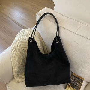 Detail of minimalist black matte suede hobo bag with leather handle and silver eyelets