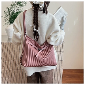 Detailed view of pink pleated tote bag with adjustable strap worn by a model