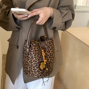Detail of leopard print bucket bag with drawstring, wooden beads, and flower charm