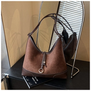 Close-up of large dark brown suede tote bag with leather patchwork and metal ring detail
