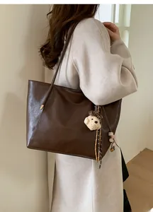 Grand sac cabas marron foncé avec breloque ours en peluche porté à l'épaule pour le style