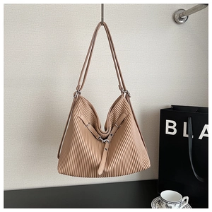 Detailed view of apricot pleated tote bag with vertical textures and metal buckle strap