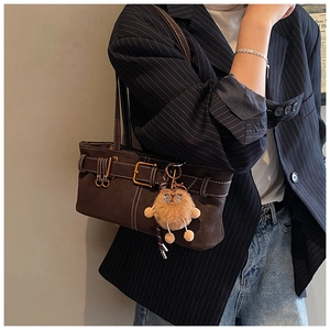 Detail of dark brown matte bucket bag with white contrast stitching and plush animal charm