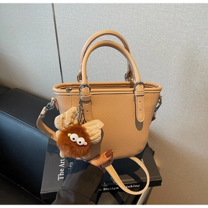 Detail of apricot pebbled leather tote bag with a cute brown plush pompom charm