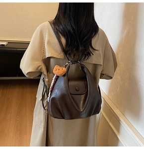 Detail of dark brown faux leather tote with plush bear charm and silk scarf handle accent