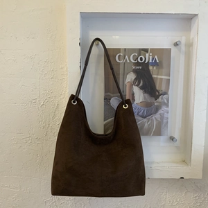 Detail of vintage dark brown suede hobo tote showing metal eyelets and stitching