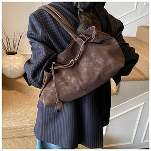 Detail of dark brown oil wax leather tote bag with stylish side decorative straps
