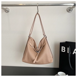 Detailed view of the vertical pleated texture and metal buckle on the apricot tote bag
