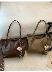Détail de grands sacs cabas en marron et olive avec des breloques ours en peluche