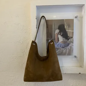 Detailed view of brown suede tote bag featuring a silver metal ring buckle and leather strap