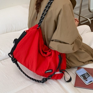 Detail of red nylon tote bag with patterned rope strap and fashion label on side