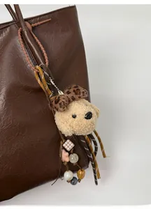 Détail d'un charme chien en peluche avec nœud léopard sur un sac fourre-tout