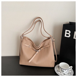 Detail of light khaki pleated tote bag with silver metal eyelets and crossbody strap