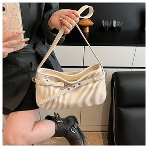 Detailed view of cream-colored pleated shoulder bag with vertical texture and metal buckle
