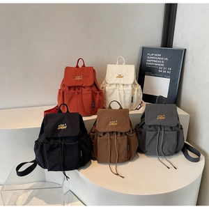 Group display of canvas backpacks in five colors with drawstring and embroidery detail