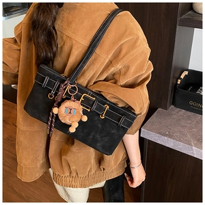 Detail of black suede shoulder bag with belt buckle and cute brown plush charm