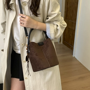Detail of dark brown matte bucket bag with leather tassels and black strap